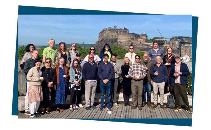 A group of people smile at the camera with Edinburgh castle in the background.