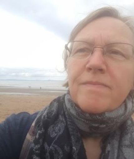 Jackie Gulland looking into the distance, behind is a sandy beach