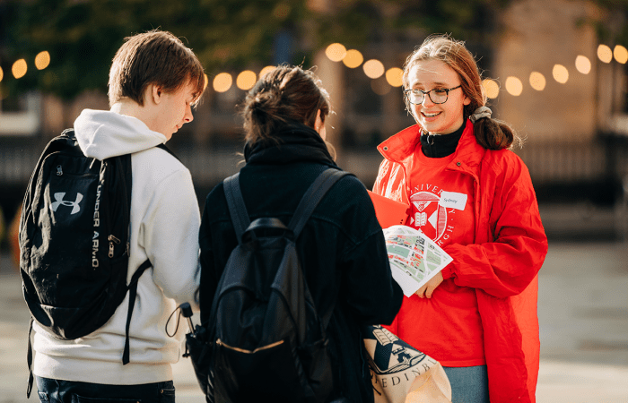 A student ambassador speaks to two visitors.