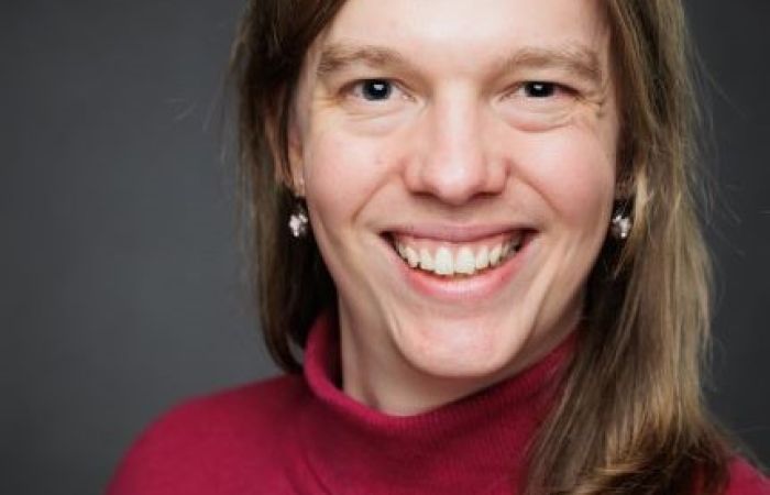 A light-skinned person with long brown hair smiling into the camera.